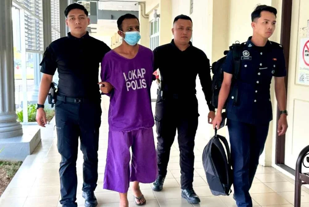 Anggota polis mengawal ketat tertuduh ketika berjalan menuju ke lokap mahkamah.