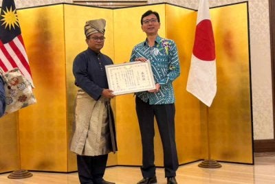 Isrami kiri ketika menerima plak penghargaan daripada Shikata Noriyuki.