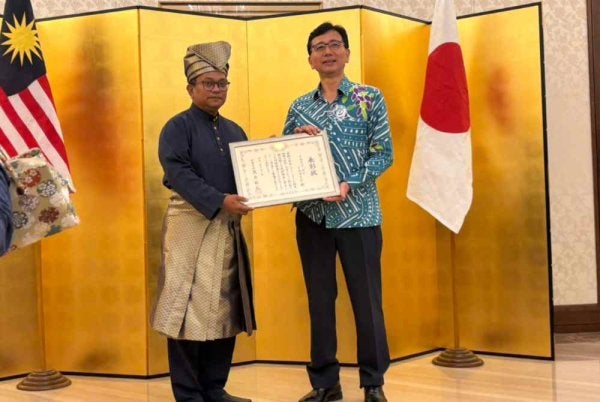 Isrami kiri ketika menerima plak penghargaan daripada Shikata Noriyuki.