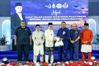 Mohamad (tiga dari kiri) menyampaikan bantuan kepada salah seorang penerima pada Program Jelajah Zakat MAINPP bersama warga TUDM yang diadakan pada Jumaat.