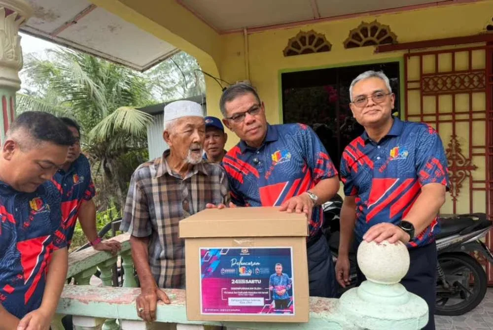 Saifuddin (dua dari kanan) menyerahkan sumbangan kepada penduduk di Kampung Melayu Sedenak, Kulai.