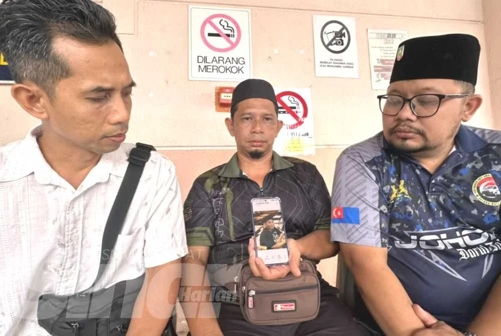 Noor Wandi (tengah) menunjukkan gambar arwah anaknya, Putera Muhaimin yang terkorban dalam nahas di Jalan Johor Bahru-Melaka, Bagan, Batu Pahat.