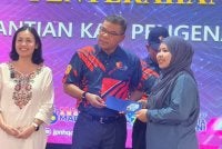 Saifuddin (tengah) menyerahkan Mykad generasi baharu di Dewan Serbaguna Kampung Melayu Sedenak, Kulai.