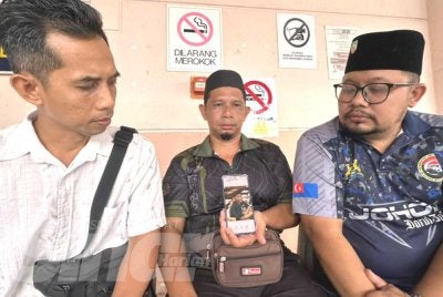 Noor Wandi (tengah) menunjukkan gambar arwah anaknya, Putera Muhaimin yang terkorban dalam nahas di Jalan Johor Bahru-Melaka, Bagan, Batu Pahat.