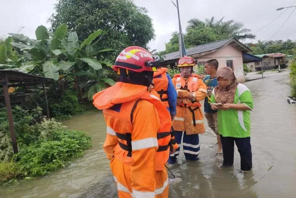 Anggota APM memindahkan mangsa banjir kilat di Kuala Muda pada Ahad.