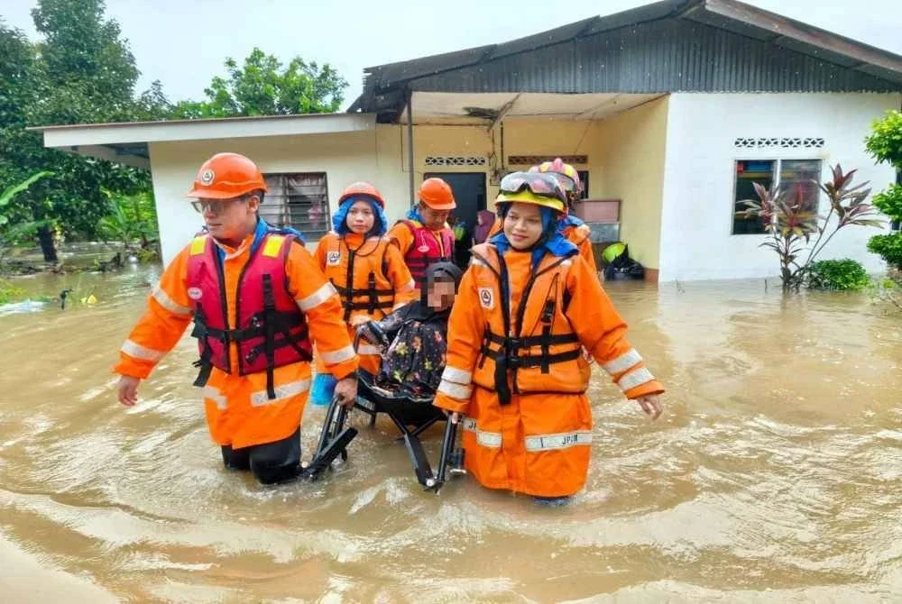 Anggota APM memindahkan mangsa banjir kilat di Yan pada Ahad.