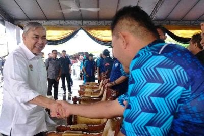 Ahmad Zahid (kiri) ketika hadir menyempurnakan penyampaian hadiah kepada pemenang Larian Jambatan Sultan Nazrin Shah Daerah Bagan Datuk di Tapak Pasar Malam Bagan Datuk pada Ahad.