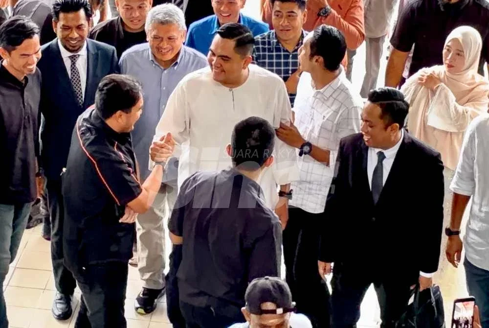 Muhamad Akmal (tengah) disambut beberapa ahli Pemuda UMNO Pulau Pinang ketika tiba di pekarangan Kompleks Mahkamah Bukit Mertajam pada Isnin.