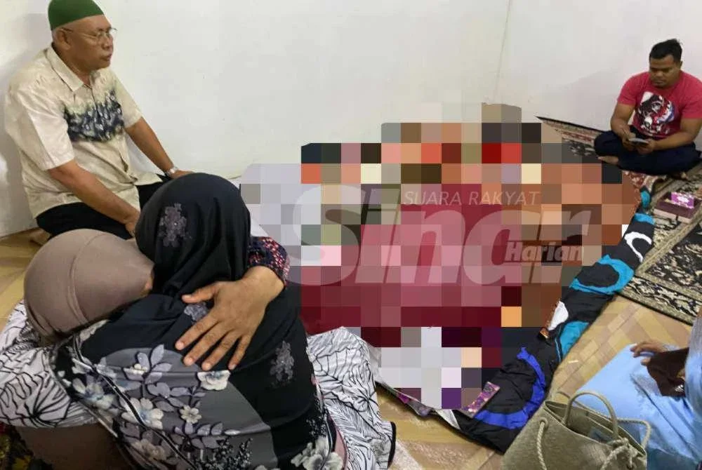 Seedah (kiri,tudung coklat) tidak dapat menahan sebak dan memeluk ahli keluarga ketika melihat jenazah anak sulung serta bongsunya di rumahnya di Kampung Era, Kuala Krai. Foto:SINAR HARIAN/HAZELEN LIANA KAMARUDIN
