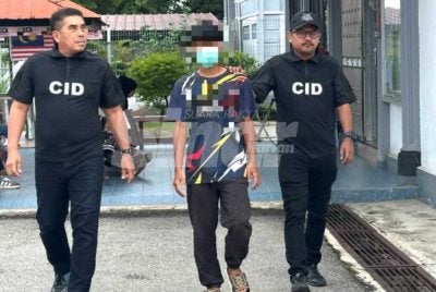 Tertuduh (tengah) dikawal polis ketika berjalan menuju ke lokap Mahkamah Machang.
