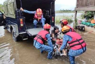 Aanggota Angkatan Pertahanan Awam bantu memindahkan mangsa terjejas di Pendang. Foto APM