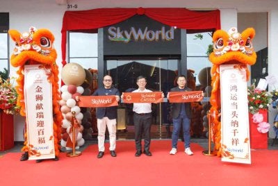 Chee Seng (kiri), Kon Yeow (tengah) dan Ketua Pegawai Kewangan SkyWorld Development Berhad, Low Weng Cheong (kanan) merasmikan pembukaan awal SkyWorld Gallery @ Bandar Cassia, Batu Kawan, Pulau Pinang menerusi upacara memotong reben.
