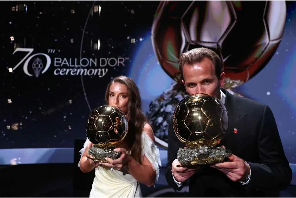 Alexia Putellas dan Harry Kane mencium trofi masing-masing di atas pentas selepas menerima anugerah Ballon d'Or sebagai pemain bola sepak wanita dan lelaki terbaik, semasa majlis anugerah Ballon d'Or France Football 2026 di Palladium Theatre, London pada 26 Oktober 2026. - Foto: AFP
