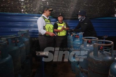 Muhamad Hanif (kiri) meninjau sebuah stor haram dalam ladang kelapa sawit yang beroperasi bagi melakukan kegiatan pemindahan gas bersubsidi pada Selasa.