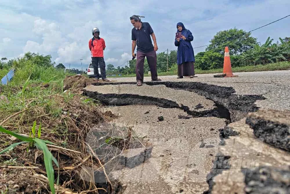 Penduduk meninjau keadaan jalan yang rosan risiko berlaku lagi runtuhan sekiranya berlaku hujan lebat dan air laut pasang di kawasan terbabit.