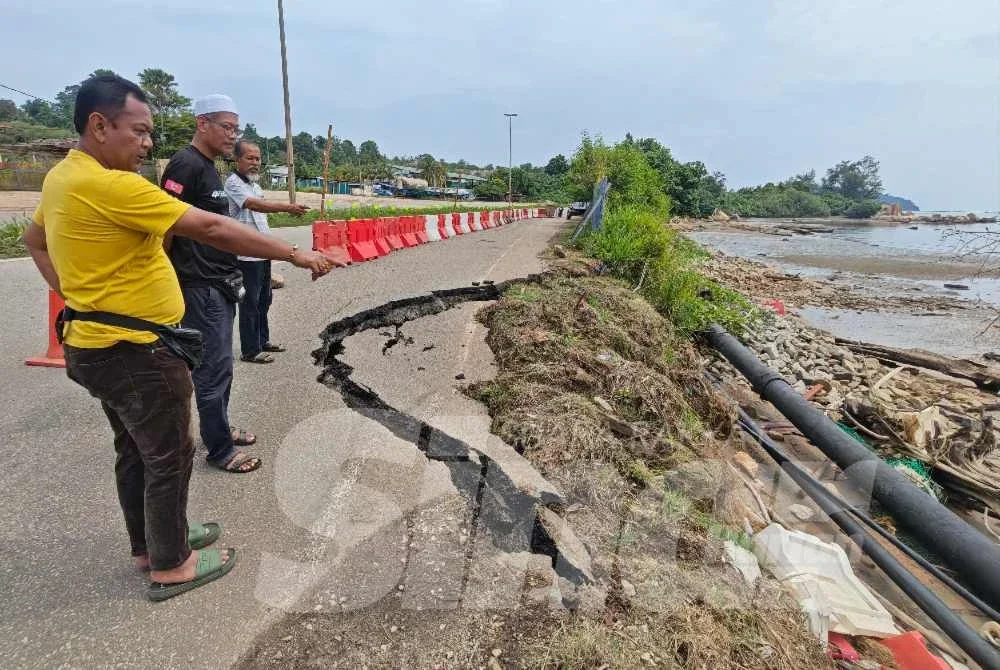 Abdul Aziz (kiri) bersama penduduk melinat dan menunjuk ke arah bahagian bahu jalan yang mengalami retakan besar dan terancam akibat hakisan pantai dilakukan tersebut. Foto Sinar Harian.