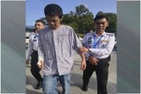Kian Wai (kiri) dibawa polis ke mahkamah untuk pertuduhan.