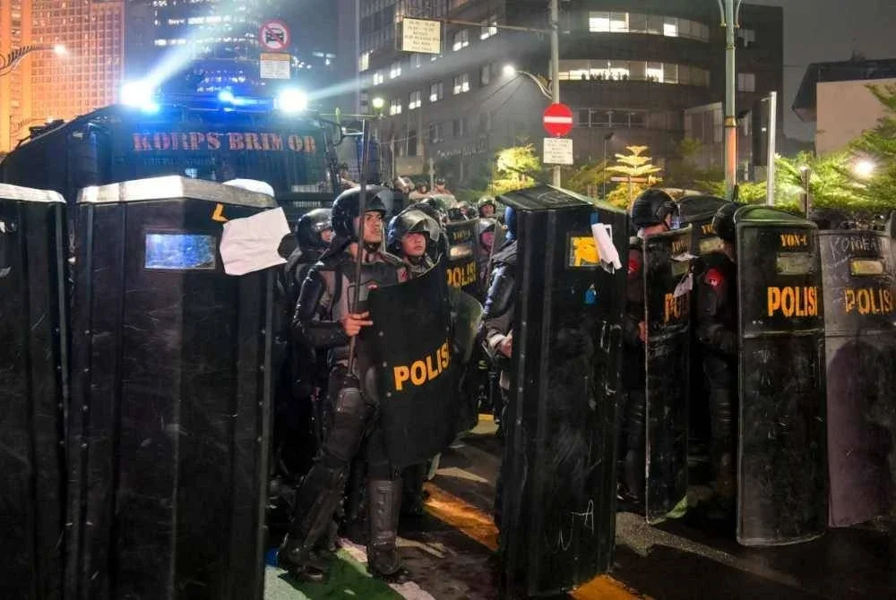 Anggota polis rusuhan membentuk benteng menggunakan perisai dengan sokongan kenderaan meriam air ketika demonstrasi. - FOTO: AFP