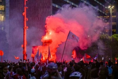 Penunjuk perasaan menyalakan suar sambil mengibarkan bendera ketika demonstrasi. Foto: AFP