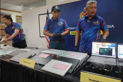 Zakaria (kanan) menunjukkan antara barang kes yang dirampas susulan tangkapan warga asing membabitkan sindiket penipuan dalam talian.