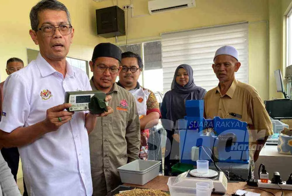 Luqman (kiri) menunjukkan alat yang digunakan untuk menguji tahap kelembapan padi semasa mengadakan lawatan ke Kilang Padi Darul Naim Sdn Bhd, Mukim Tasek Berangan di Pasir Mas pada Rabu.