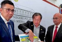Mooi Lye (kiri), Chin Kooi (tengah) dan Rajendran menerangkan langkah mitigasi yang diambil pada kawasan runtuhan di Taman Sri Rambai, Paya Terubong Ahad lalu.