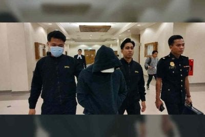 Tertuduh diiringi pegawai SPRM keluar dari Mahkamah Sesyen di Kuantan pada Jumaat.